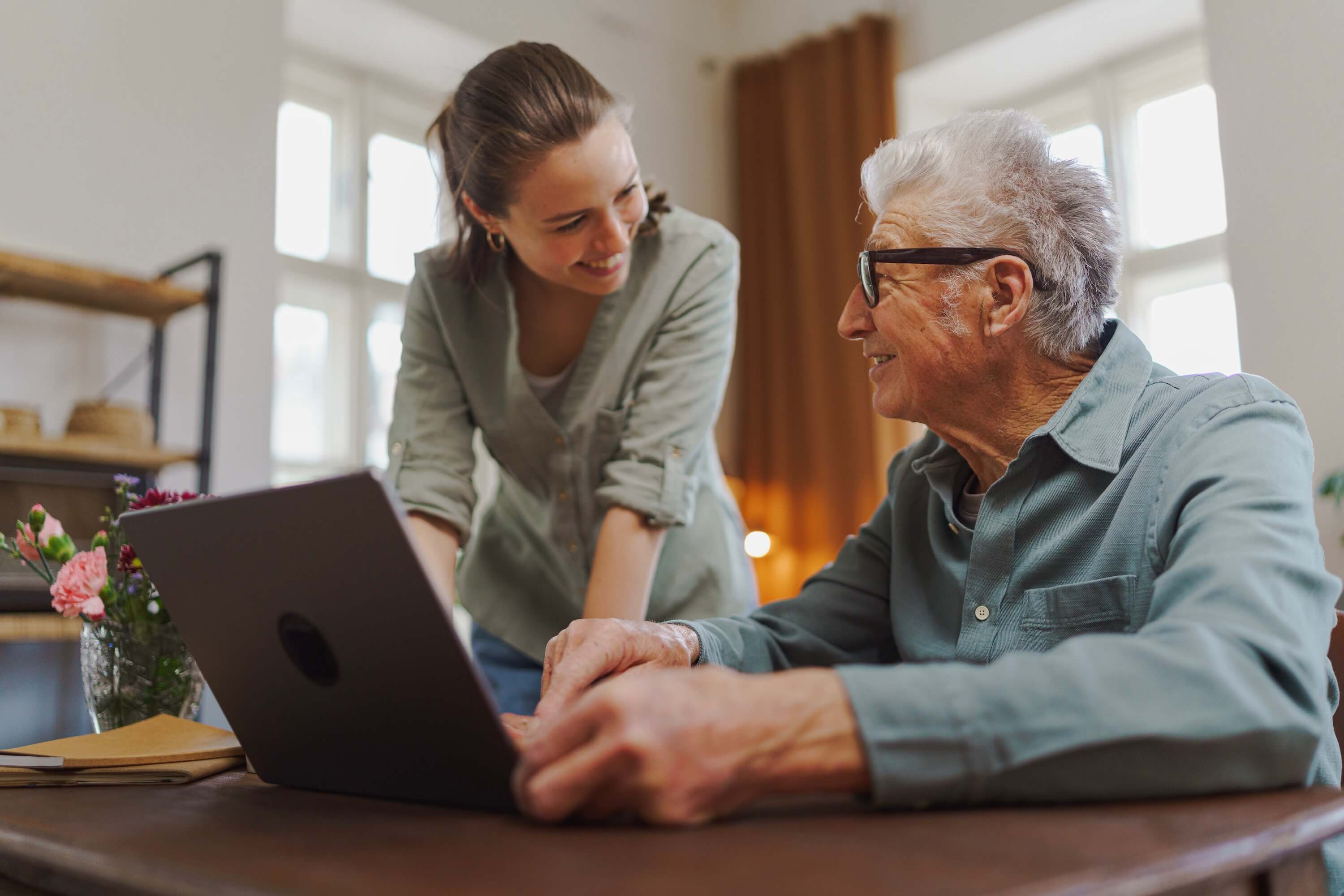 Granddaughter showing something to her grandfather on a laptop