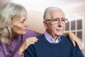elderly woman consoling elderly man